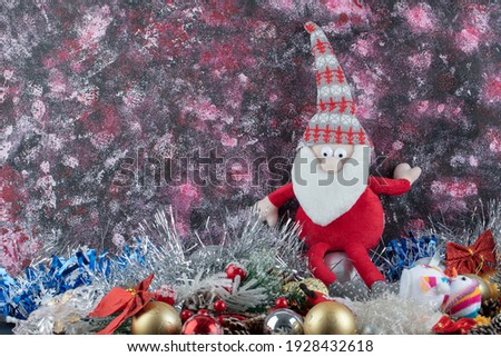 Small Santa figurine and baubles on colorful background