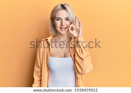 Young blonde girl wearing casual clothes smiling positive doing ok sign with hand and fingers. successful expression. 