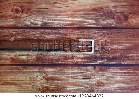 Brown leather belt on the wooden background