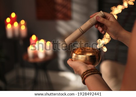 Healer using singing bowl in dark room, closeup Royalty-Free Stock Photo #1928492441