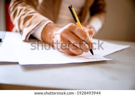 Female hand writing signature on the paper document. Cut out Woman signs agreement or formulary contract. Paperwork concept Royalty-Free Stock Photo #1928493944