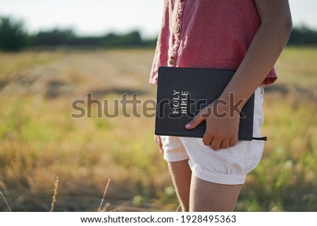 Christian girl holds bible in her hands. Reading the Holy Bible in a field. Concept religion.