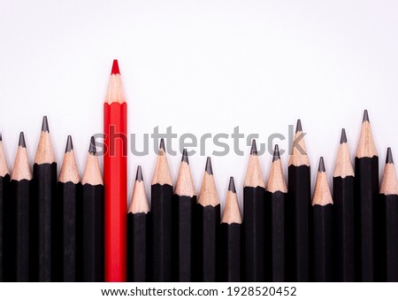Red pencil standing out from black pencil fellows on white background, uniqueness, leadership, independence, think difference, find the way to the winner, business successfuly in life. Royalty-Free Stock Photo #1928520452