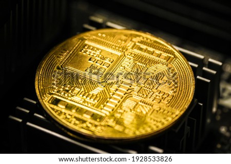 Big cryptocurrency golden coin placed on back side of the system board, close up macro view.
