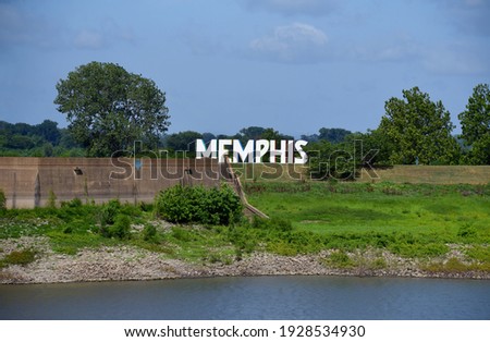 Large sign on Mud Island River Park says Memphis.  Mississippi River can be seen in foreground.