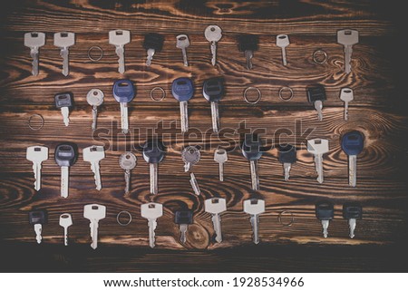 A studio photo of a broken key among many normal keys on a wooden background. Photo in the old style with vignetting.
