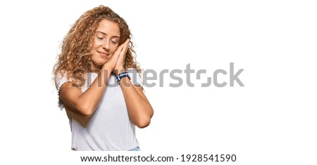 Beautiful caucasian teenager girl wearing casual white tshirt sleeping tired dreaming and posing with hands together while smiling with closed eyes. 
