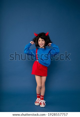 Spoiled child, naughty girl, kids whims. Beautiful little girl in wig with red imp horns showing character. Child crisis psychology concept. Full length photo