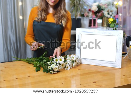 florist girl in an apron to work on creating a creative bouquet for a client. online order preparation concept. Space for text