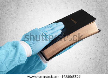 Doctor in uniform holding a bible and praying with hope.