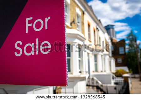 Estate agent For Sale sign on street of houses