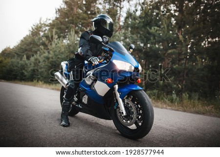Black motorcycle driver in helmet and leather outfit Royalty-Free Stock Photo #1928577944