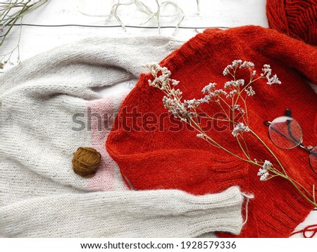 Mess on the knitter's table, unfinished projects and baby sweater on white wooden background