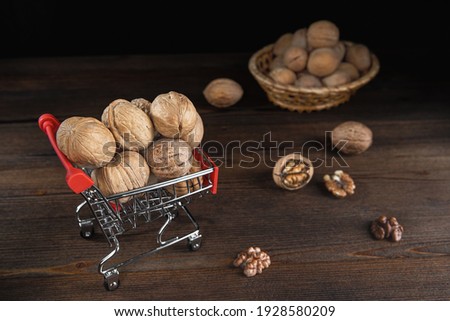 Walnuts in metal trolley on dark wooden background, selective focus