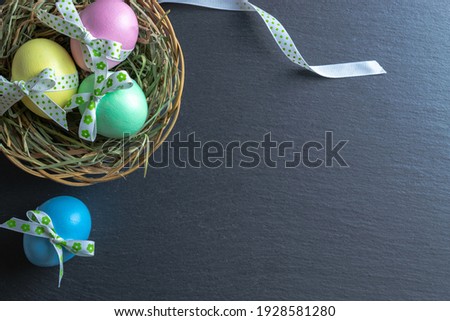 Easter egg hunt. Colorful egg with tape ribbon on dark rough stone background in Happy Easter decoration. Traditional design in top view