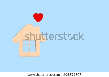 Wooden house and a red heart. A symbol of happiness in the family, warmth of a sweet home, love and relationships. Mortgage, insurance, care, eco, sale real estate minimalistic background, copyspace.