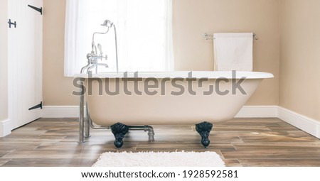 Modern bathroom interior design with clawfoot bath tub and floor tiles. Luxury, contemporary bathrooms, UK.  Royalty-Free Stock Photo #1928592581