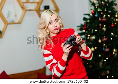 Close female portrait with beautiful smile with dimples and curls on blond hair. Woman holds camera lady photographer. Concept of happiness, new year, christmas, photographer works.