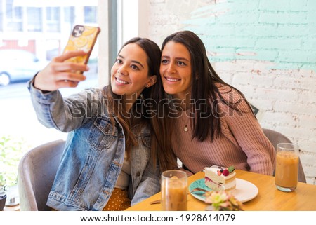 Portrait of two beautiful girlfriends taking selfie photo in a coffee shop