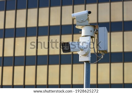 Surveillance cameras in the city in front of a modern administrative building.
