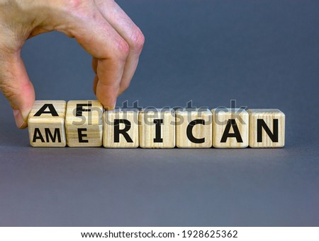 African american symbol. Businessman turns wooden cubes with words 'african american'. Beautiful grey background. Business and african american concept. Copy space.