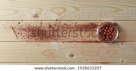 Makeup brushes with cosmetic face powder and blusher balls on wooden plank table surface, boards background and texture