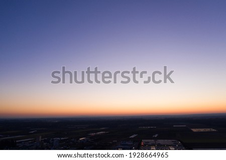 aerial panorama picture of a deep blue sky with the horizon being orange lit by the setting sun 