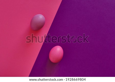 Abstract combined violet-pink background with diagonal. Painted violet egg on a pink background, painted pink egg on a violet background. Top view. Easter holiday concept.