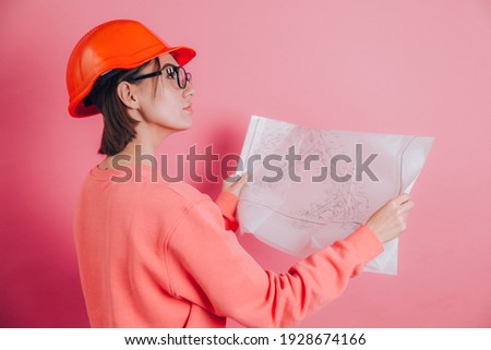 Smiling woman worker builder against pink background. Building helmet.