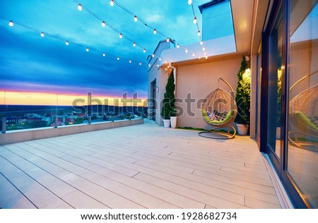 rooftop deck patio area with hanging chair and lights on a sunset