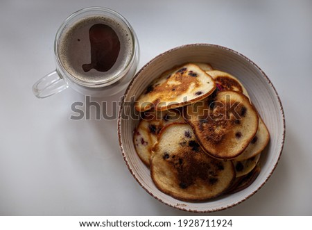 Pancakes with berries in a plate. Coffee in a transparent cup. Breakfast