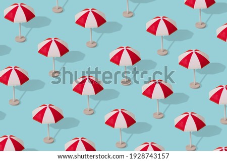 Creative idea, a pattern of colorful umbrellas on a light blue background. Minimal summer vacation concept. 