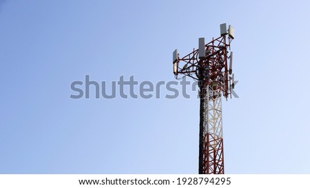 Telecommunication towers. A 4 G or 5 G wireless telephone communication transceiver on a red and white metal column. On a blue sky background with a copy space. Selective focus Royalty-Free Stock Photo #1928794295
