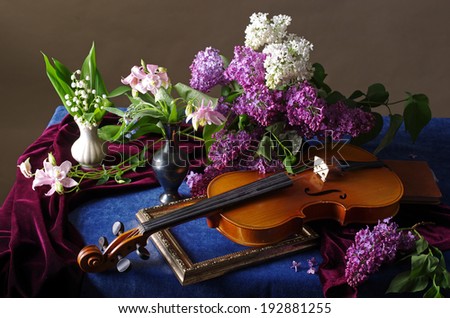 Still life with bunch of lilac, lily of the valley and violin on the blue table-cloth