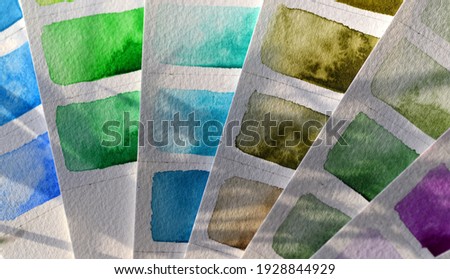 Color palette close-up watercolor on white paper, green and blue shades. Sunlight falls on the paper, shadows from plant leaves, beautiful paint streaks, granulation.
