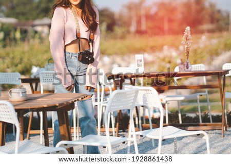 Travel, technology and lifestyle concept: Portrait of a photographer girl hanging camera in cafe.