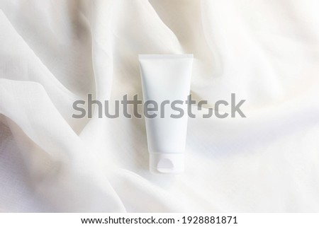 white cosmetic tube for face cream, cleanser, body lotion or shampoo on white draped cloth. Gentle skin care concept. Copy space Royalty-Free Stock Photo #1928881871