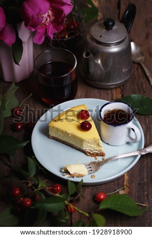 cheesecake on a plate and cup with cherries and a bouquet of peonies nearby
