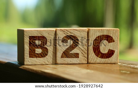 B2C letters on wooden cubes put on wooden table standing outdoors. Summer nature background. Business to Customer concept. Client oriented.