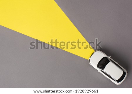 Top flat lay view photo of toy mini car driving on grey road with headlights on isolated background with copy empty space Royalty-Free Stock Photo #1928929661