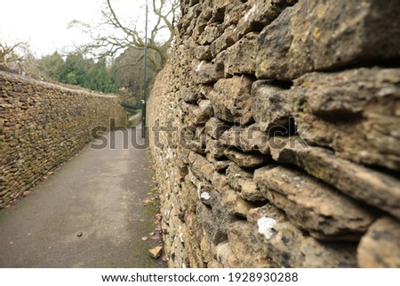 Old stone wall on side of a pedestrian walkway  Close-up on the stone side with wide angle view