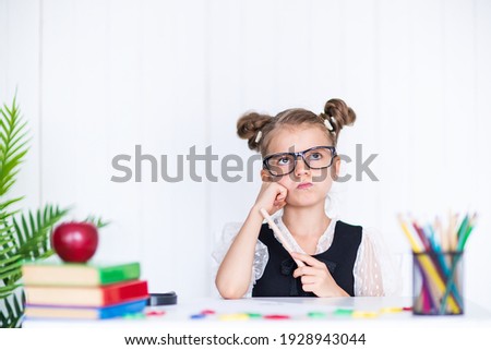 Thoughtful pupil at the desk. Girl in the class room with pencils, books. Kid girl from primary school. first day of fall. Back to school.