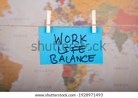 
Work Life Balance word written on a Blue color sticky note hanging with a wire in front of world map background