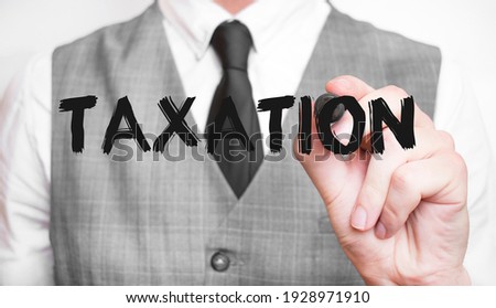Businessman writing word TAXATION with marker, Business concept