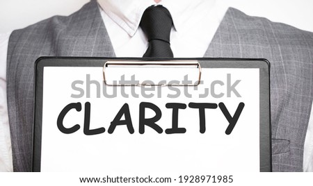 Businessman holding sheet of paper with a message CLARITY