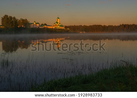 View of the Holy Trinity Alexander Svirsky monastery from the opposite shore of the Roshchinsky lake in purple shades. Holy Trinity Alexander Svirsky Monastery in the Leningrad region. Royalty-Free Stock Photo #1928983733