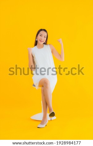 Portrait beautiful young asian woman in action on yellow isolated background