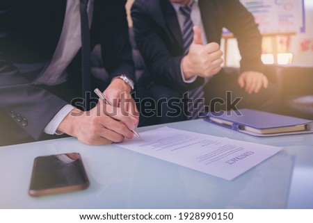Businessman puts signature on contract at business meeting and passing money after negotiations with business partners. Selected focus