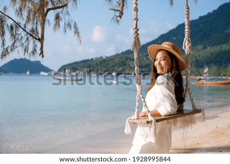 Portrait image of a beautiful young asian woman with swing by the sea