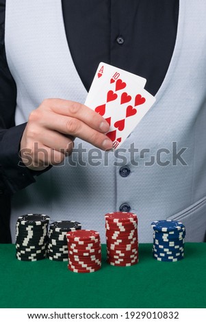 a croupier in a white vest holds victory cards in the game
